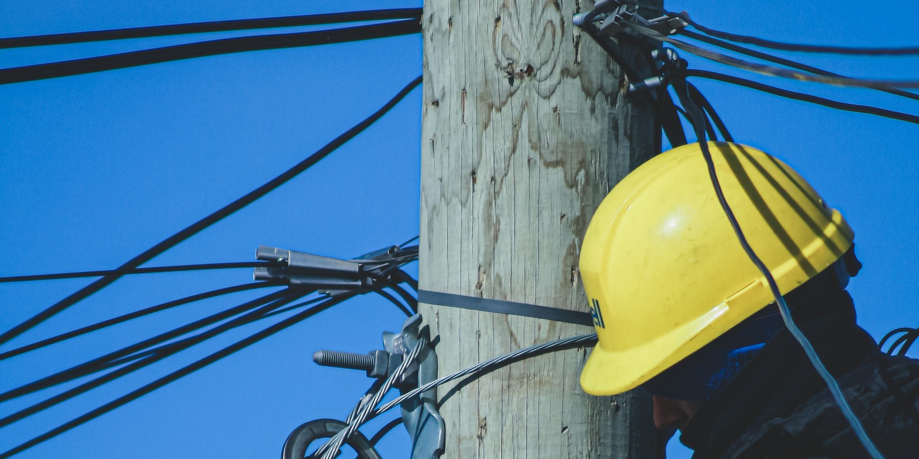 Técnico con casco trabajando en cables de un poste (imagen ilustrativa)